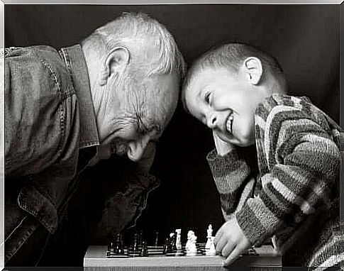 Grandfather playing chess with his happy grandson