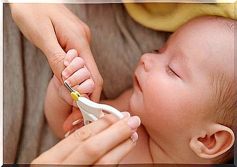 Mom cuts the nails of the newborn