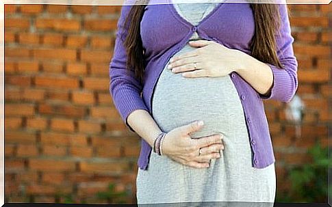 Pregnant woman touching her belly;  what is the right age to become a mother?