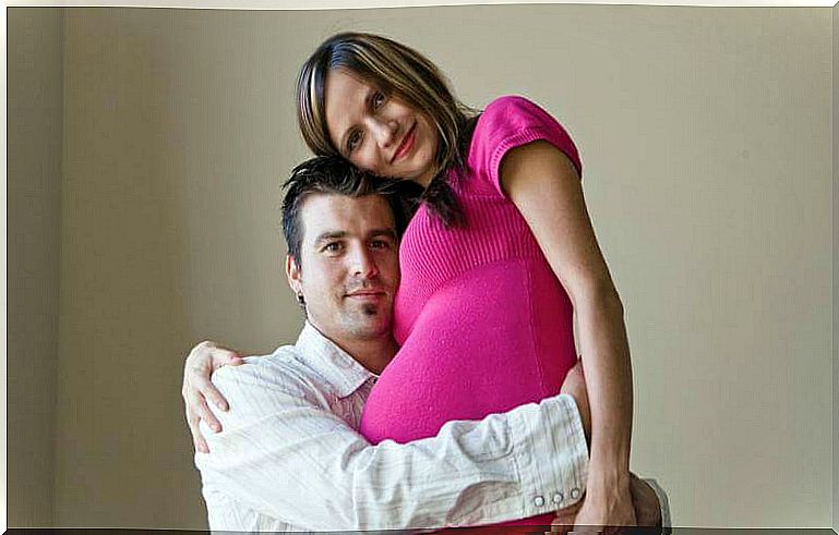 A father hugs a pregnant mother, parents after 40