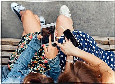 two little girls on a bench play with their smartphones