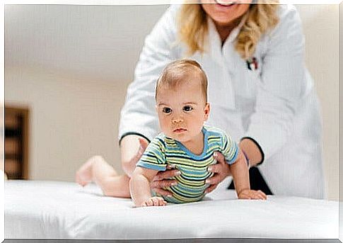 Woman pediatrician holds baby on cot